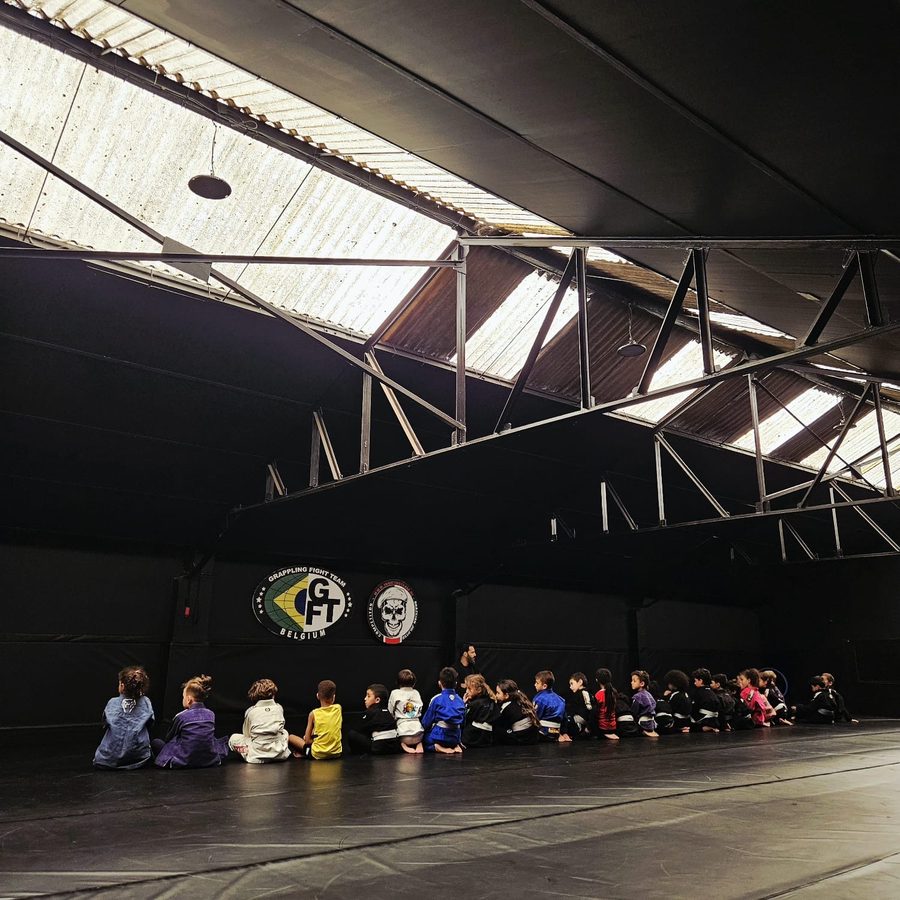 Élèves assis en ligne devant le coach, sous les logos Grappling Fight Team